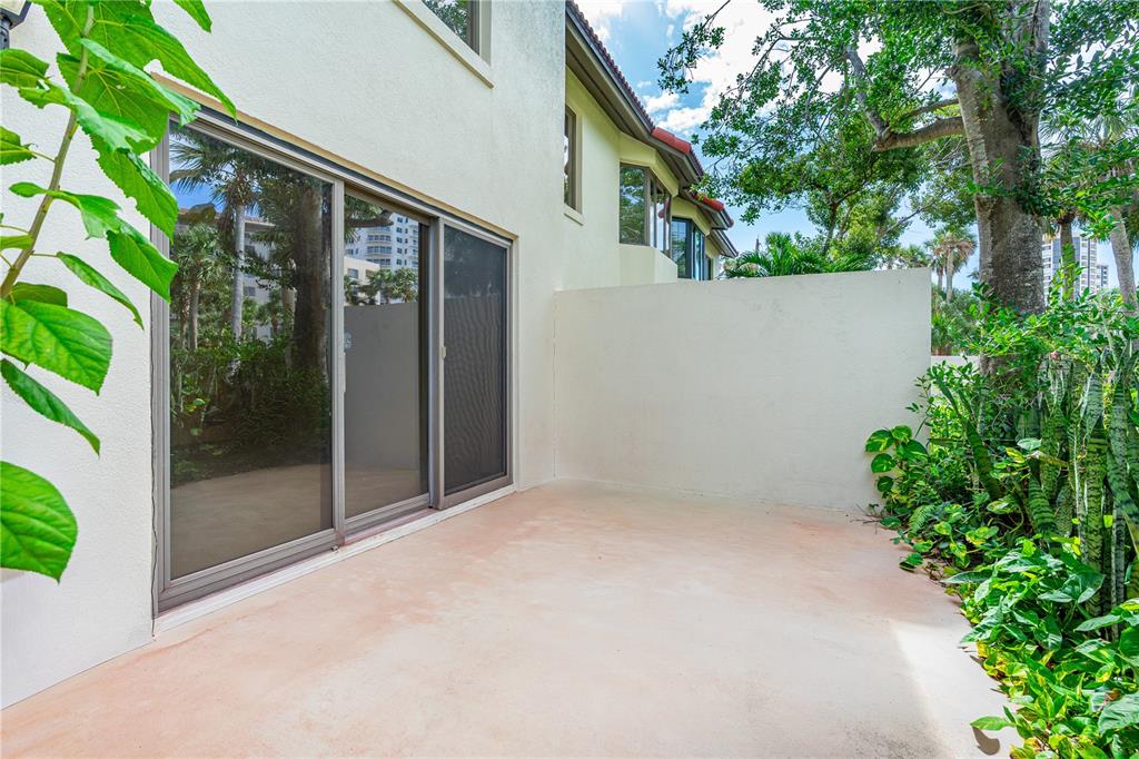 A concrete patio sits beside a building with sliding glass doors and a privacy wall — 2966 OCEANS TRACE, DAYTONA BEACH SHORES, FL
