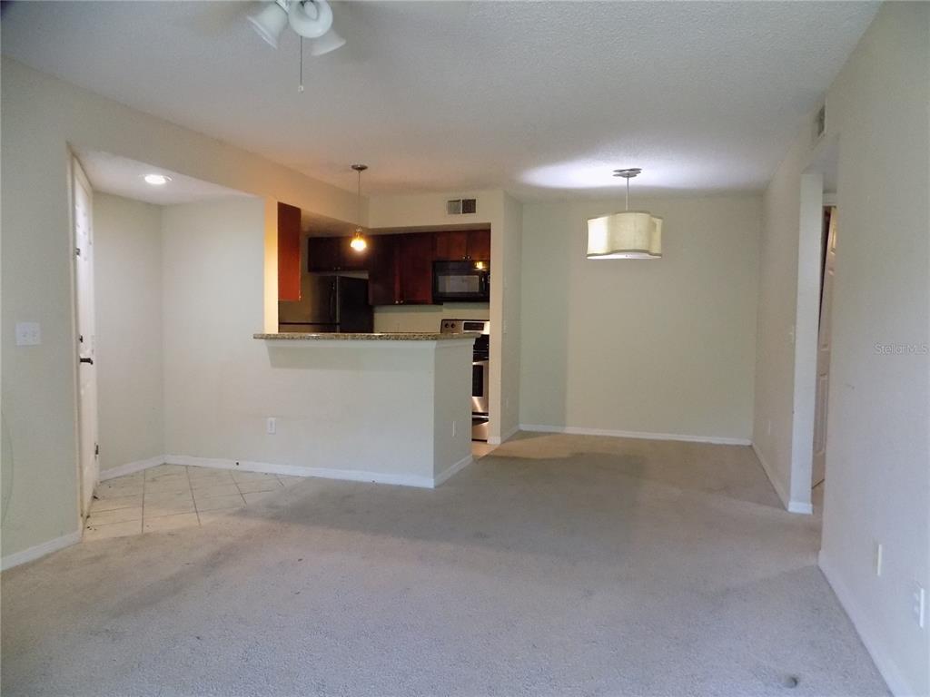 An interior view shows a carpeted living area, a dining space, and a kitchen pass-through — 5116 CONROY ROAD UNIT 16, ORLANDO, FL