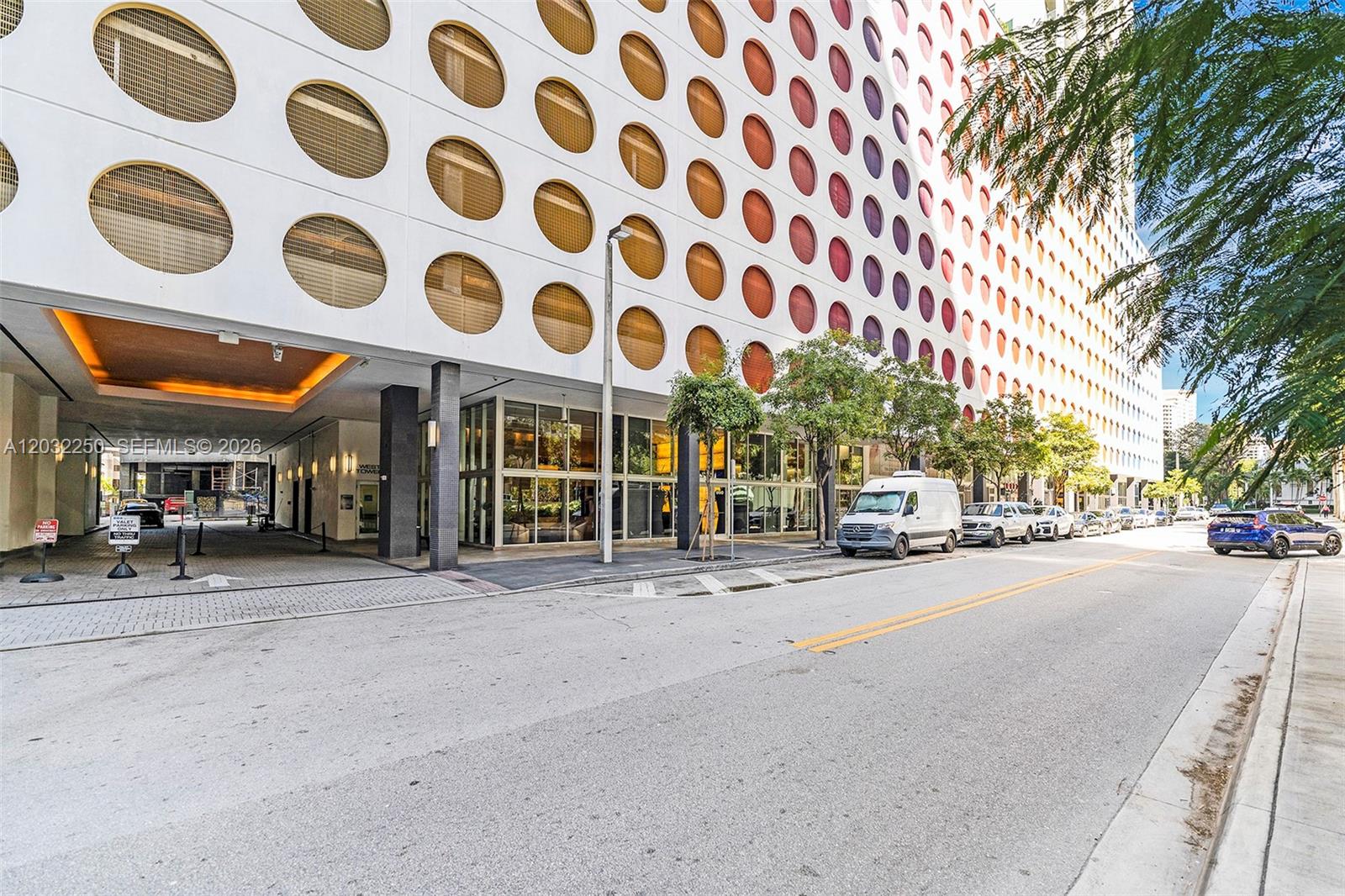 The exterior of a modern building features a white facade with repeating circular windows — 55 SE 6th St # 1208, Miami FL 33131, MIAMI, FL