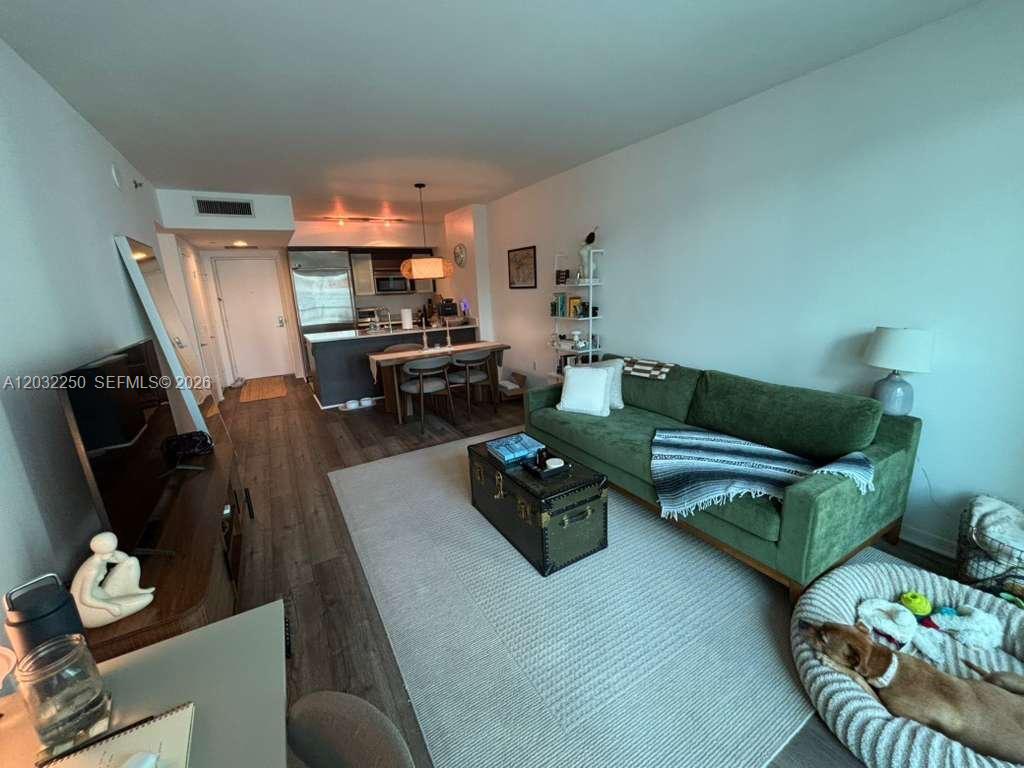 A living room features a green sofa, a trunk coffee table, and an open kitchen — 55 SE 6th St # 1208, Miami FL 33131, MIAMI, FL