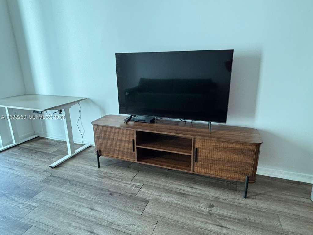 A television sits on a wooden media console next to a white desk — 55 SE 6th St # 1208, Miami FL 33131, MIAMI, FL