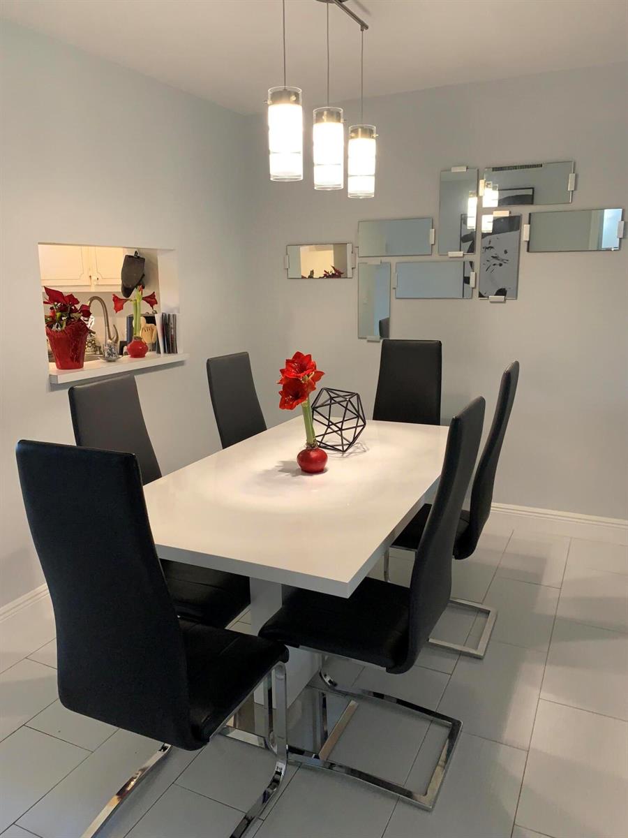 A dining room features a white table, black chairs, pendant lighting, and a mirrored wall — 2500 Fiore Way # 109, Delray Beach FL 33445, DELRAY BEACH, FL