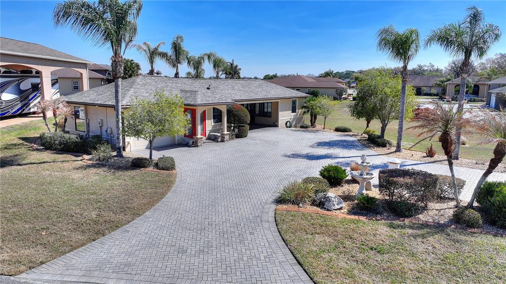 A single-story house with a paved driveway, palm trees, and a covered carport area — 561 MEANDERING WAY, POLK CITY, FL