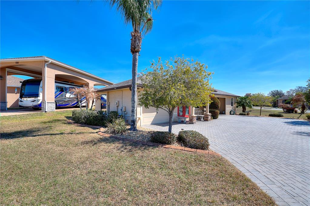 A house exterior features a large RV carport, a paved driveway, and a palm tree — 561 MEANDERING WAY, POLK CITY, FL