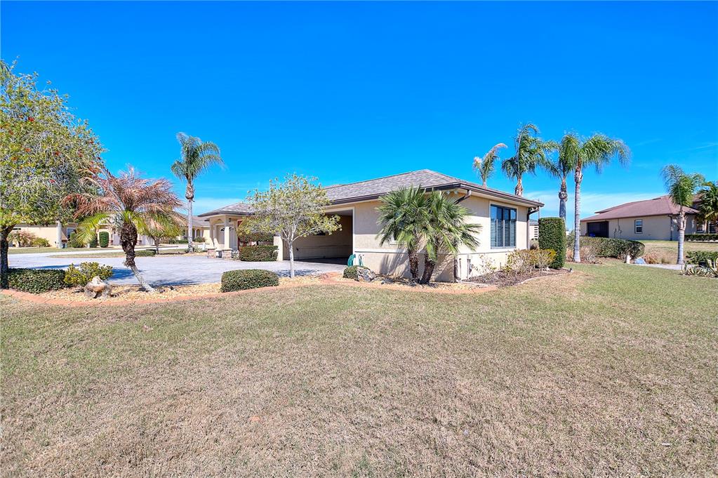 A single-story house with a beige exterior, a side-entry garage, and palm trees in Florida — 561 MEANDERING WAY, POLK CITY, FL