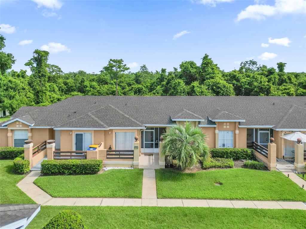 A single-story tan townhouse with a shingled roof, front patios, and a grassy lawn — 3154 SANDY SHORE LANE, KISSIMMEE, FL