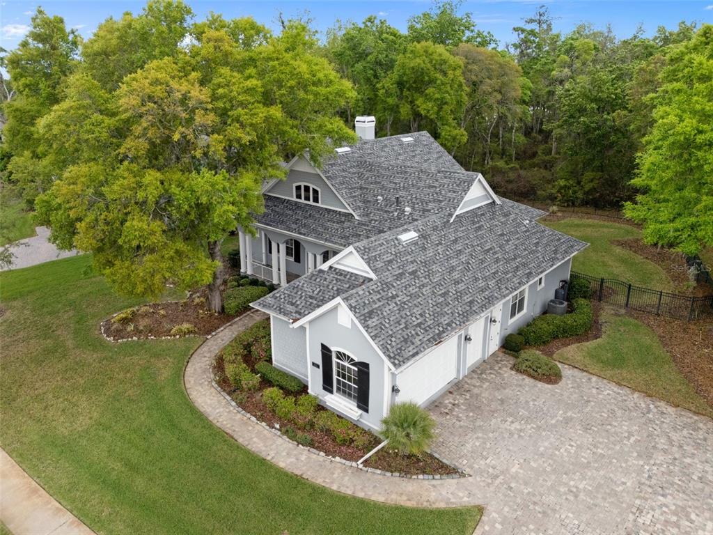 An aerial view of a gray two-story house with a shingled roof and paver driveway — 6096 DUSK ROSE LANE, BROOKSVILLE, FL