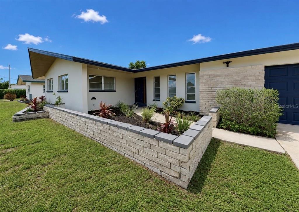 A low-slung house with a brick planter wall and a dark blue garage door — 1729 BIKINI COURT, CAPE CORAL, FL