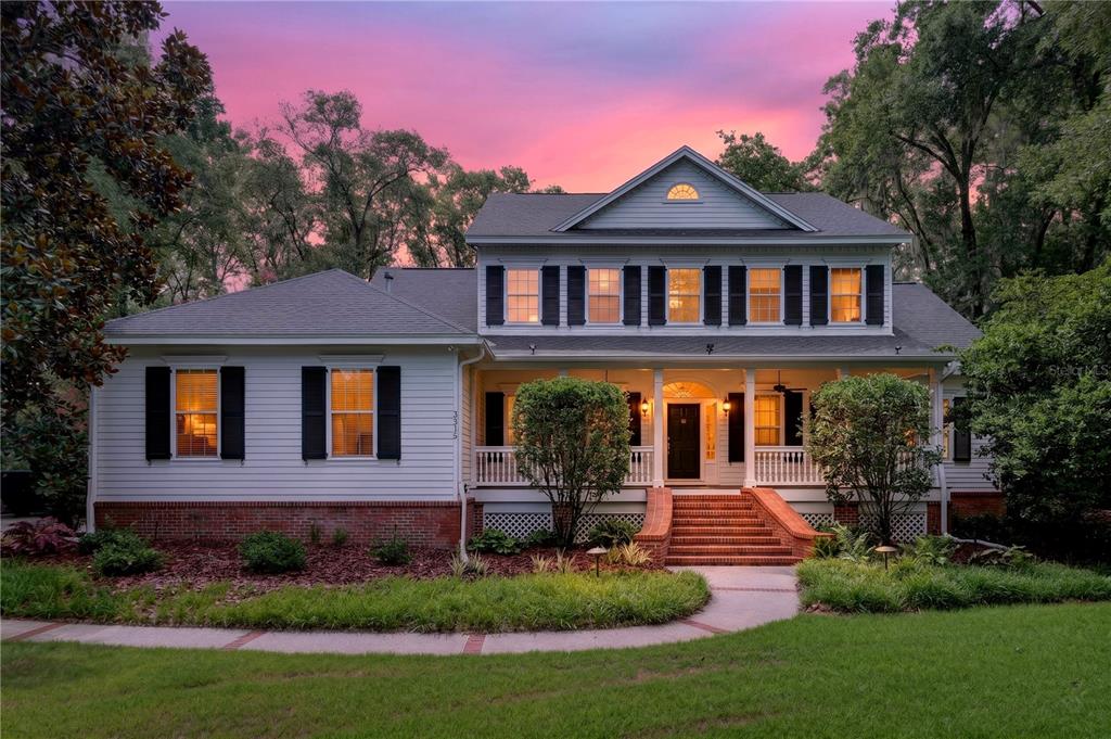 A two-story house with white siding, brick accents, and a front porch at sunset — 3915 SW 95TH TERRACE, GAINESVILLE, FL