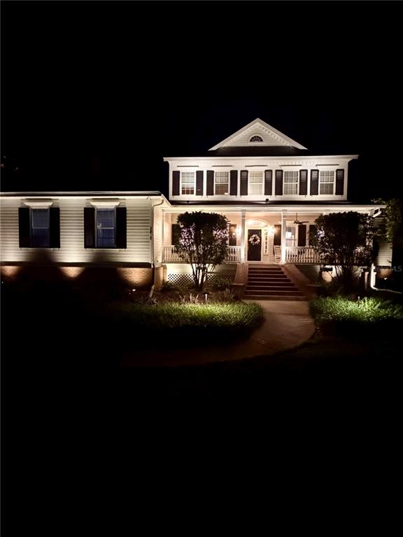 A two-story house with white siding and dark shutters is illuminated at night — 3915 SW 95TH TERRACE, GAINESVILLE, FL