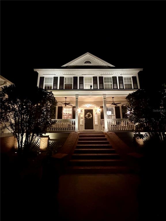 A two-story house with a front porch and stairs is illuminated at night — 3915 SW 95TH TERRACE, GAINESVILLE, FL