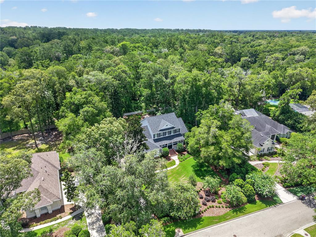 An aerial view shows a two-story house surrounded by dense trees and a paved street — 3915 SW 95TH TERRACE, GAINESVILLE, FL