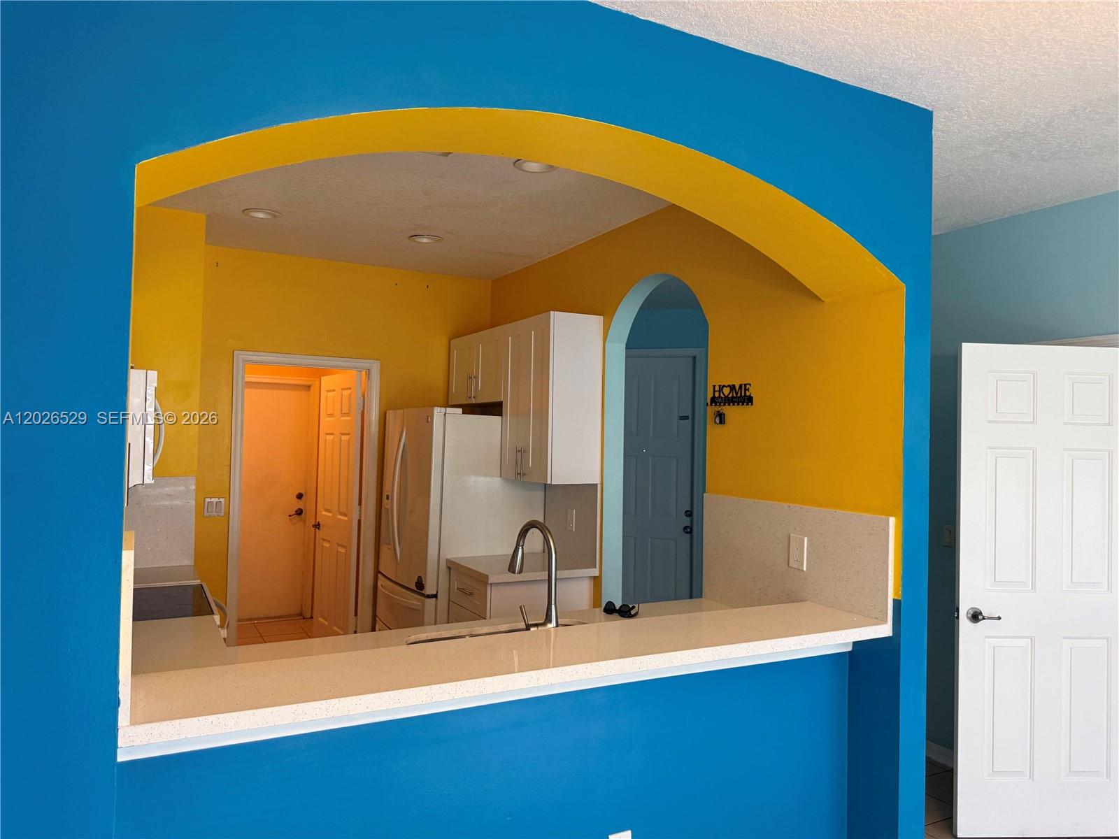 A kitchen features a yellow arched opening, white cabinets, and a light-colored countertop — 4951 Mallory St # 4951, Lake Worth FL 33463, LAKE WORTH, FL