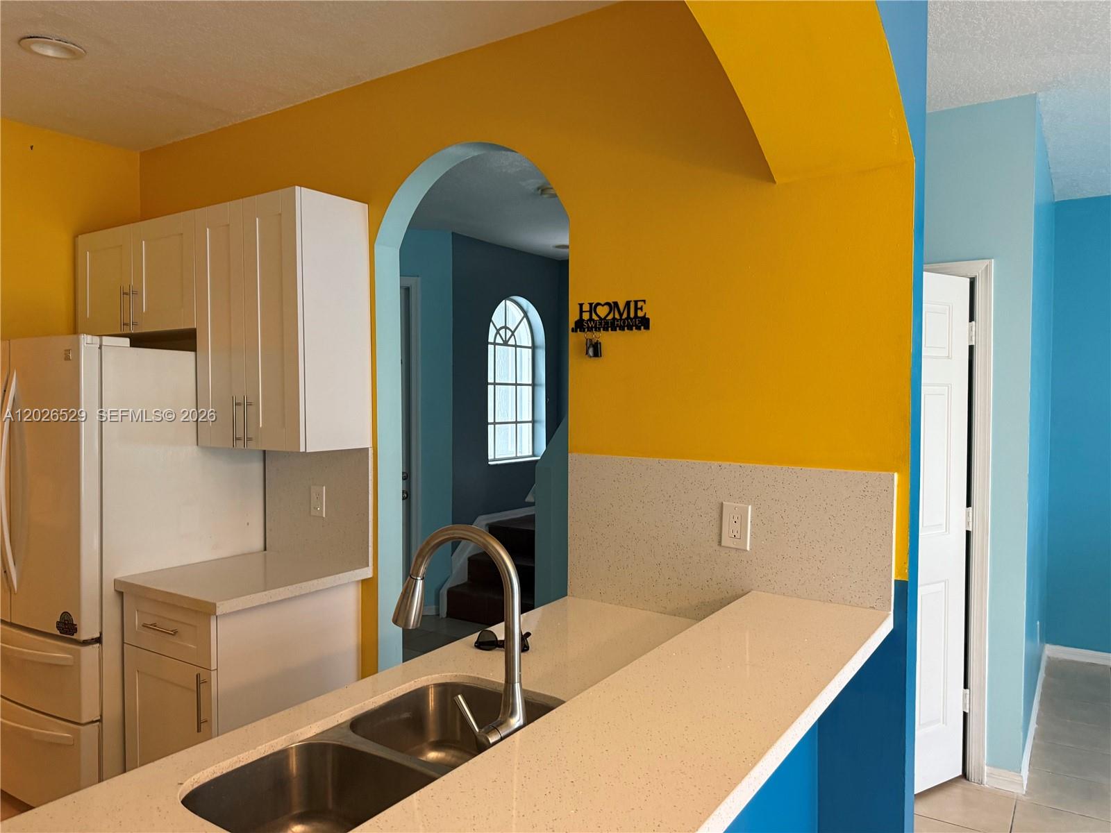 A kitchen features white cabinets, a quartz countertop, a double sink, and yellow walls — 4951 Mallory St # 4951, Lake Worth FL 33463, LAKE WORTH, FL