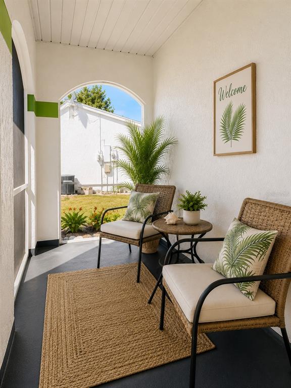 A covered patio features two wicker chairs, a small round table, and a jute rug — 8181 MARLOW COURT, NORTH PORT, FL