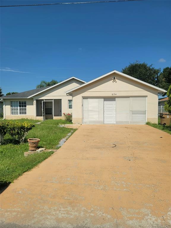 A single-story house with a beige exterior, a two-car garage, and a concrete driveway — 634 BALDWIN DRIVE, KISSIMMEE, FL