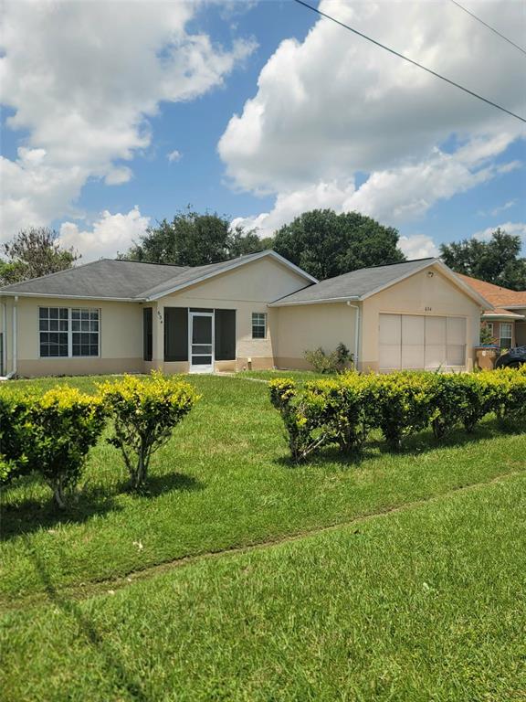 A single-story house with a beige exterior, a screened entryway, and a two-car garage — 634 BALDWIN DRIVE, KISSIMMEE, FL