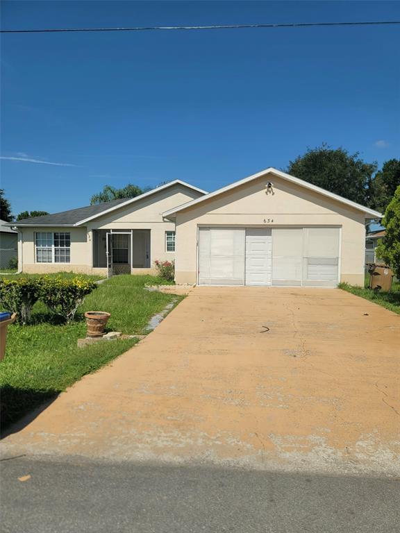 A single-story house with a beige exterior, a screened-in porch, and a concrete driveway — 634 BALDWIN DRIVE, KISSIMMEE, FL