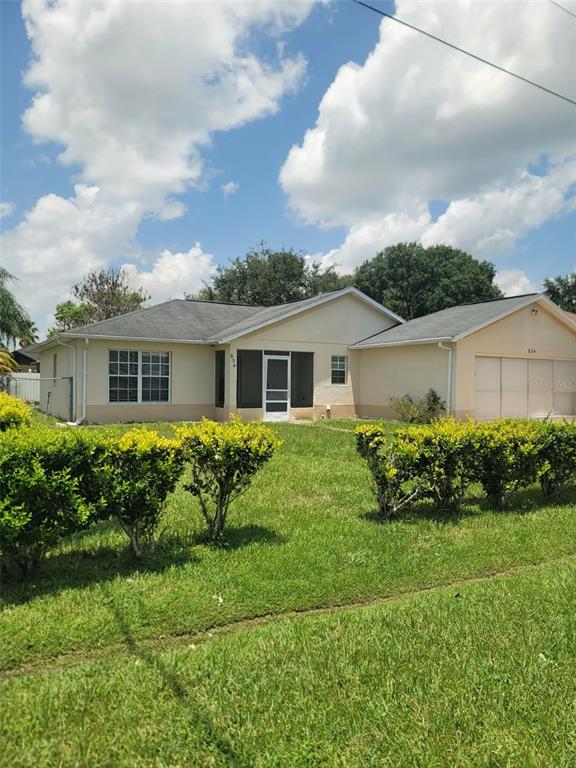 A single-story house with a beige exterior, a screened-in porch, and an attached garage — 634 BALDWIN DRIVE, KISSIMMEE, FL