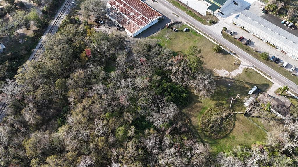 An aerial view shows a wooded lot adjacent to commercial buildings and a paved road — 713 E ALSOBROOK STREET, PLANT CITY, FL