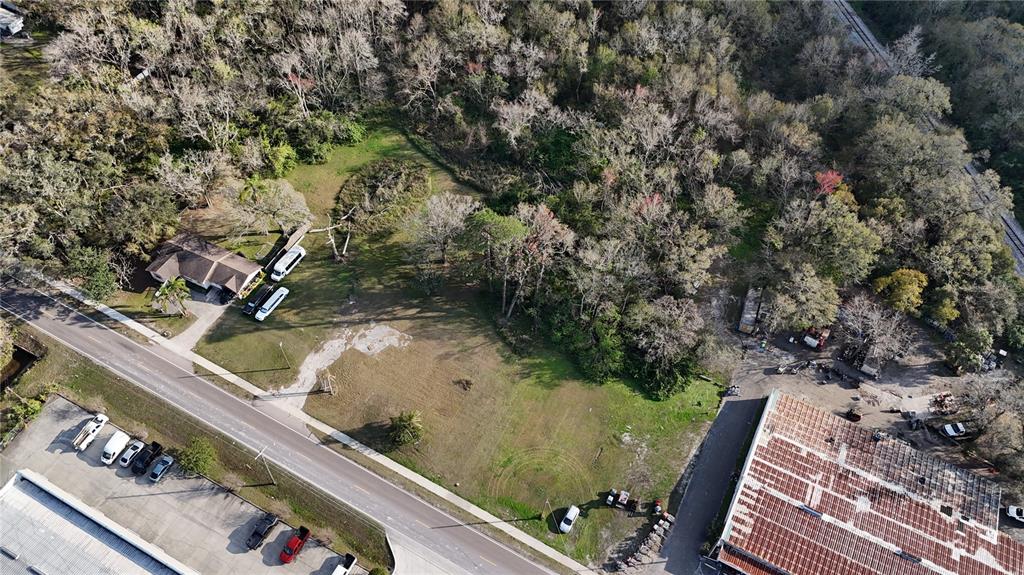An aerial view shows a house, a large grassy lot, and nearby commercial buildings — 713 E ALSOBROOK STREET, PLANT CITY, FL