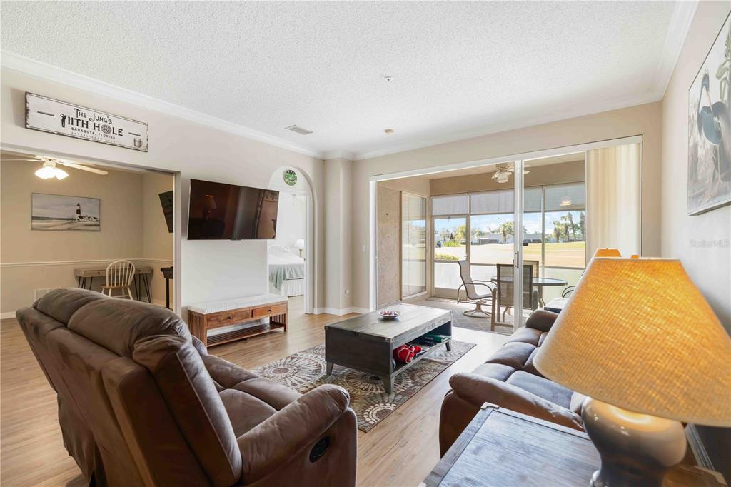 A living room features brown leather furniture, a coffee table, and a sliding glass door — 5064 MAHOGANY RUN AVENUE, SARASOTA, FL