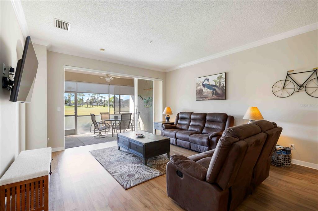 A living room with brown leather furniture, a coffee table, and a sliding door to a patio — 5064 MAHOGANY RUN AVENUE, SARASOTA, FL