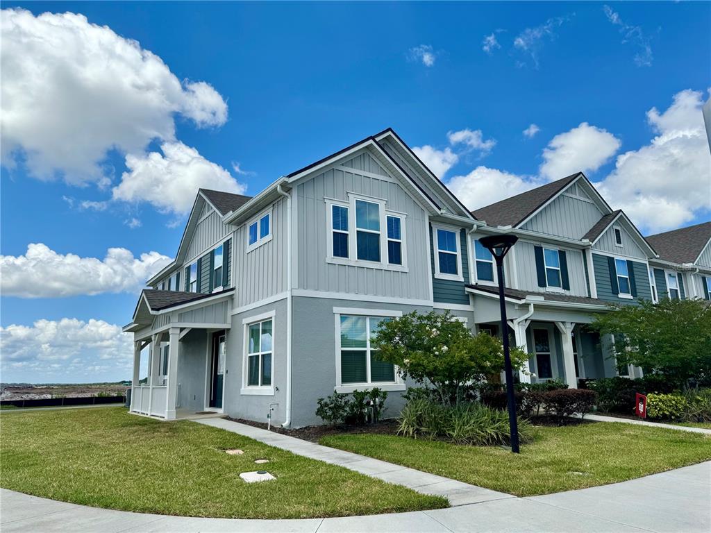 A two-story townhouse with gray siding and a concrete walkway under a blue sky — 2540 BLOWING BREEZE AVENUE, KISSIMMEE, FL