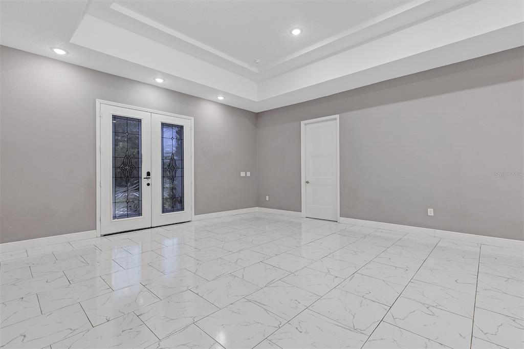 A room with light gray walls, white tile flooring, a tray ceiling, and French doors — 4501 SW 145TH PLACE ROAD, OCALA, FL