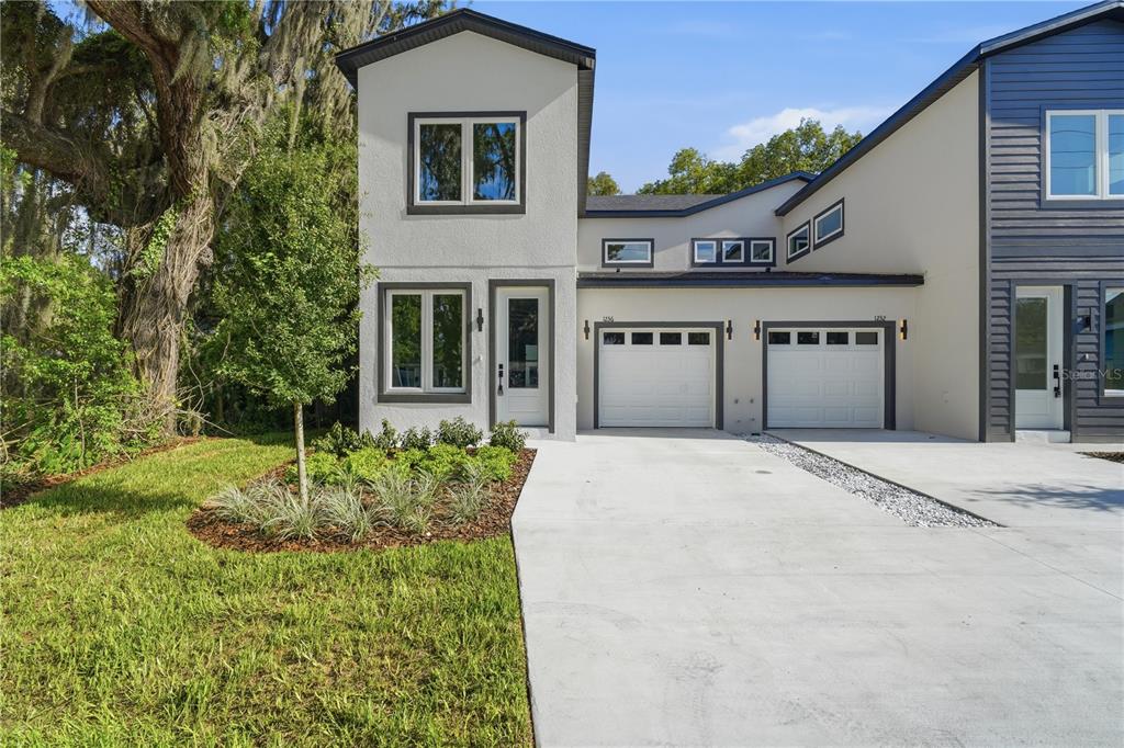 A two-story duplex with white stucco, two garage doors, and a landscaped front yard — 1236 VIRGINIA DRIVE, ORLANDO, FL