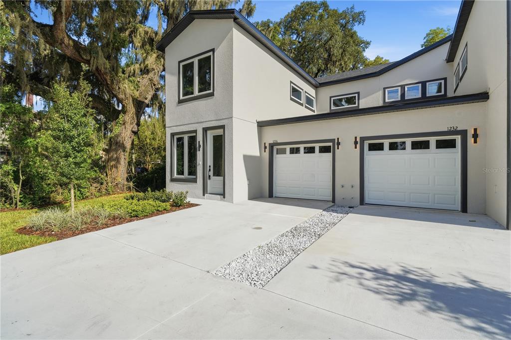 A two-story duplex with light-colored stucco siding, dark trim, and two attached garages — 1236 VIRGINIA DRIVE, ORLANDO, FL