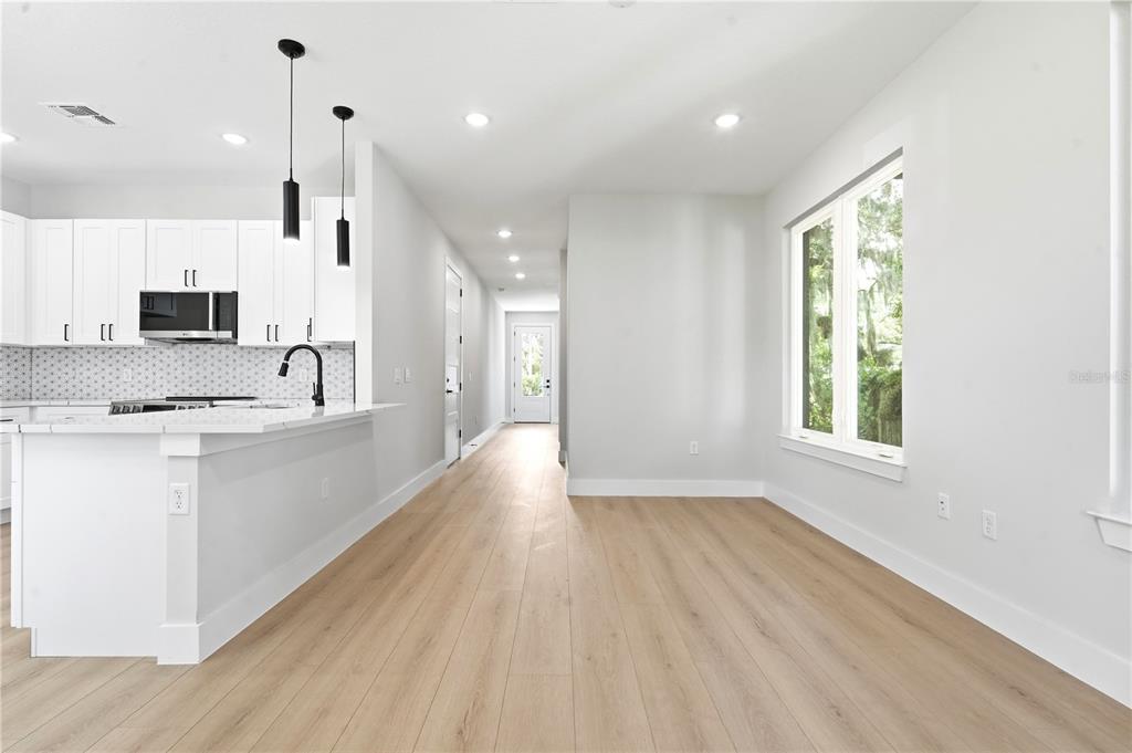 A modern kitchen with white cabinets and a dining area featuring light wood flooring — 1236 VIRGINIA DRIVE, ORLANDO, FL