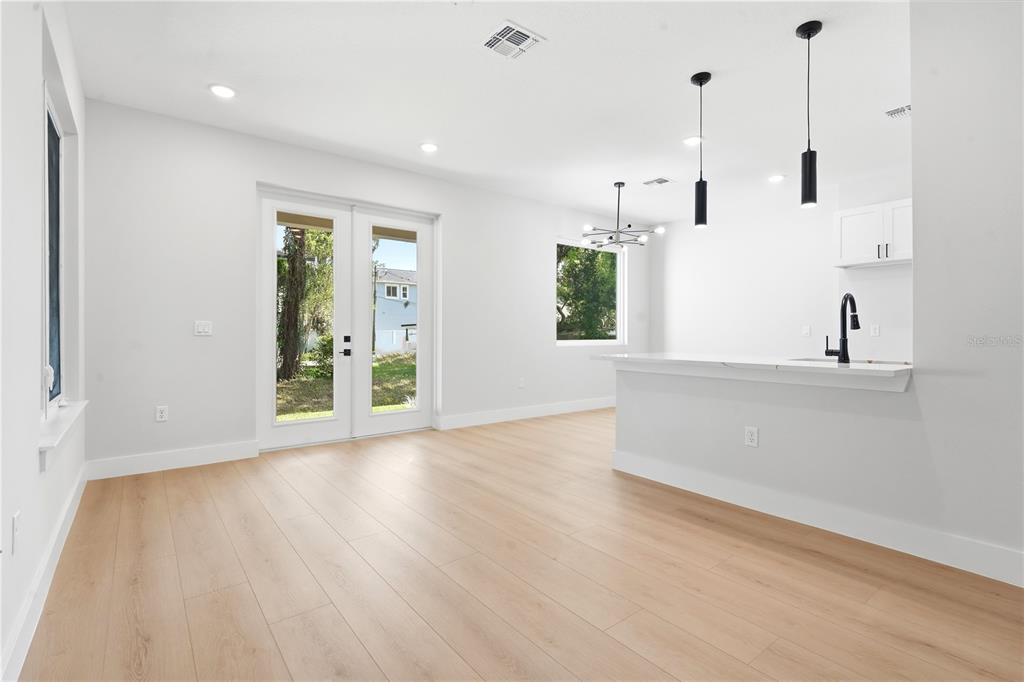 A bright, open-concept kitchen and living area featuring light wood flooring and white cabinetry — 1236 VIRGINIA DRIVE, ORLANDO, FL