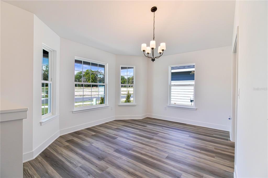 An empty dining room with white walls, wood-look flooring, a chandelier, and multiple windows — 16865 NW 176TH WAY, ALACHUA, FL