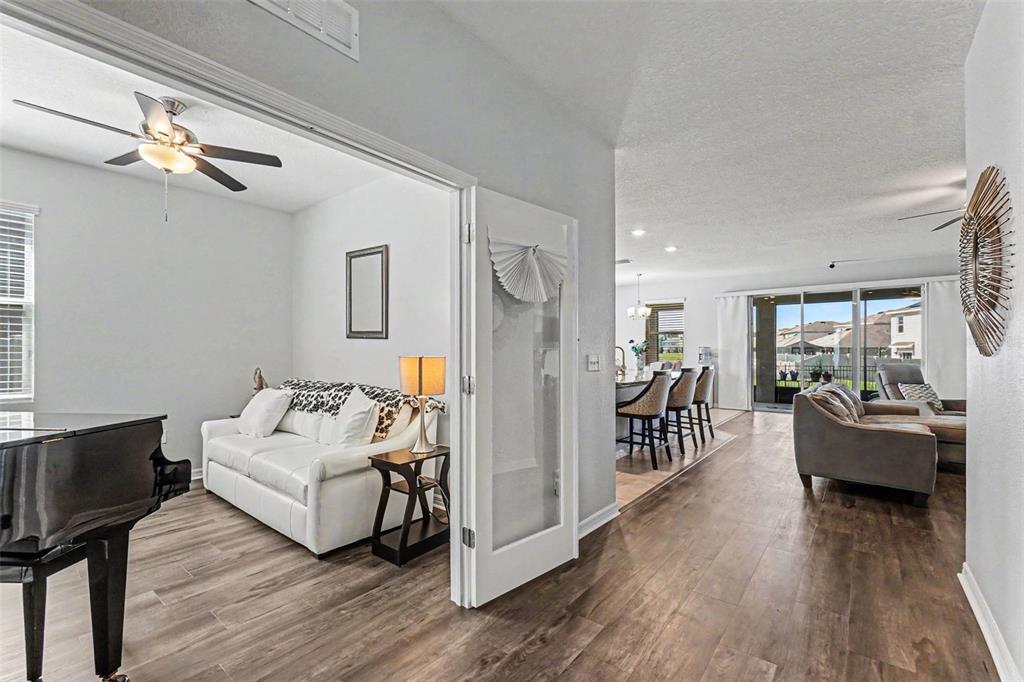 A kitchen with light cabinets and granite countertops opens to a dining area with seating — 16639 GOOSE RIBBON PLACE, WIMAUMA, FL