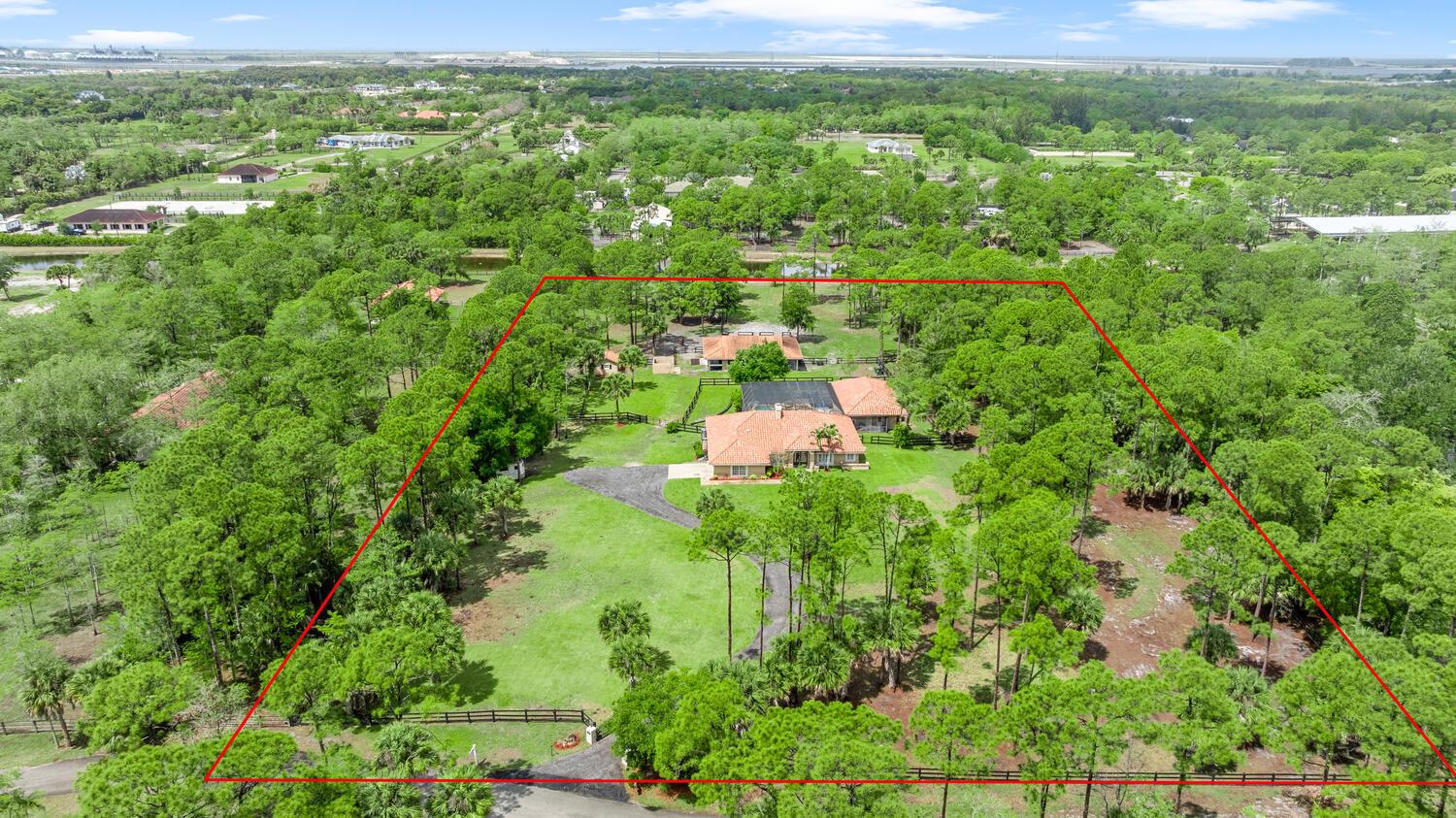 An aerial view shows a house with a red tile roof surrounded by dense trees — 2559 Palm Deer Drive, Loxahatchee FL 33470, LOXAHATCHEE, FL