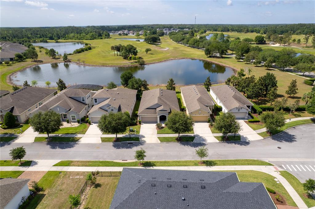 An aerial view shows a row of suburban houses overlooking a pond and golf course — 3304 SAGEBRUSH STREET, HARMONY, FL