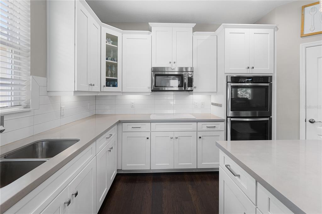 A kitchen with white cabinets, stainless steel appliances, a subway tile backsplash, and dark flooring — 3304 SAGEBRUSH STREET, HARMONY, FL