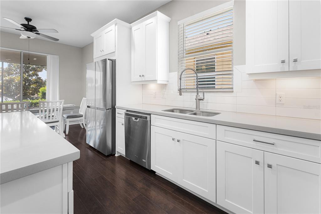 A modern kitchen features white cabinets, stainless steel appliances, and dark wood flooring — 3304 SAGEBRUSH STREET, HARMONY, FL