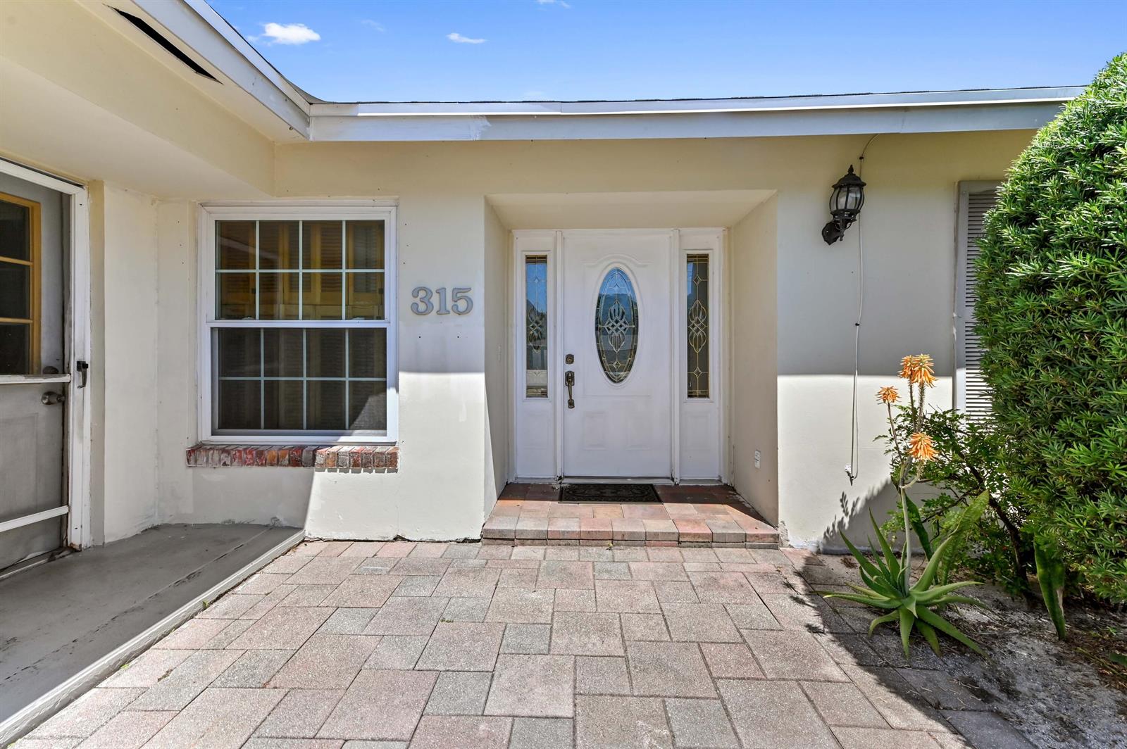 The exterior view shows a front entrance with a white door, window, and paved walkway — 315 SW 12th Avenue, Boynton Beach FL 33435, BOYNTON BEACH, FL