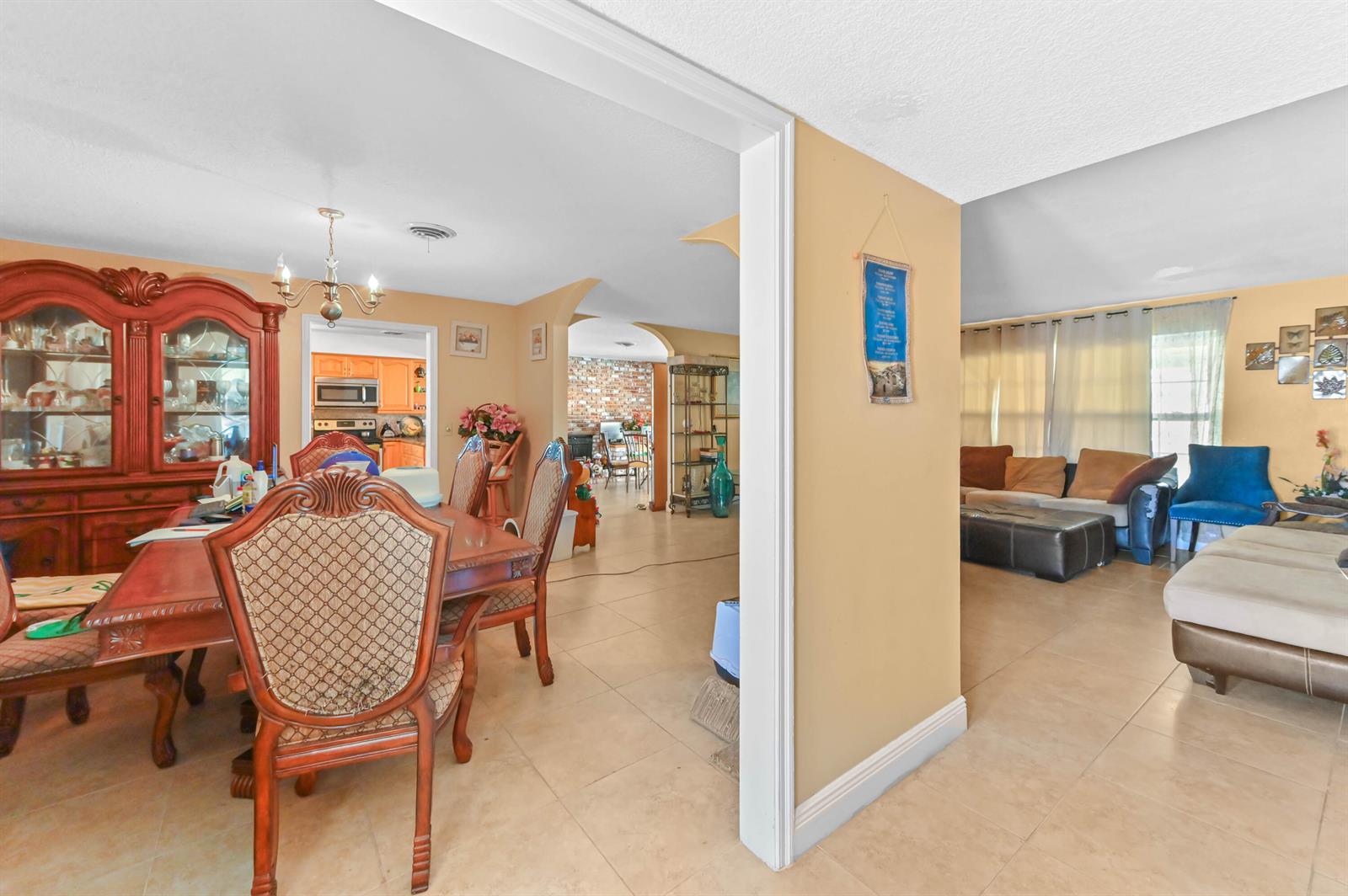 A dining room with a wooden hutch and table leads into a living area with tile floors — 315 SW 12th Avenue, Boynton Beach FL 33435, BOYNTON BEACH, FL