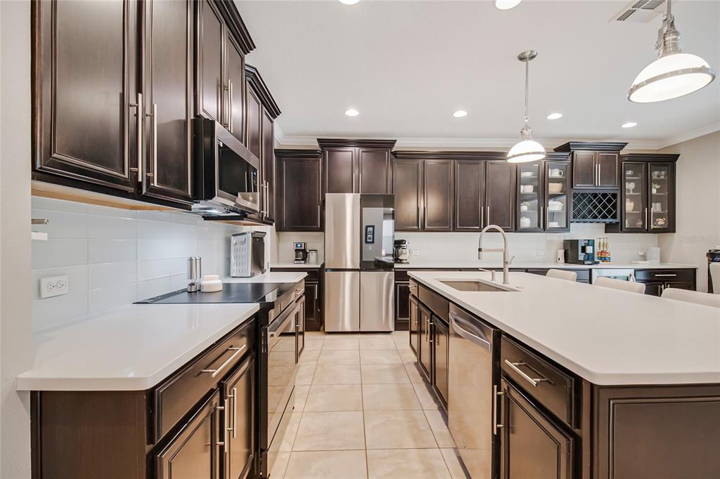A kitchen with dark wood cabinets, white countertops, stainless steel appliances, and a central island — 11763 AURELIO LN, ORLANDO, FL