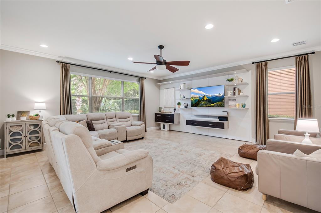 A living room features a large sectional sofa, a wall-mounted television, and tile flooring — 11763 AURELIO LN, ORLANDO, FL