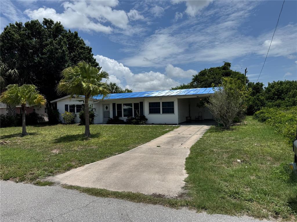A single-story house with a blue metal roof and a concrete driveway — 27233 WHITMAN AVENUE, PUNTA GORDA, FL