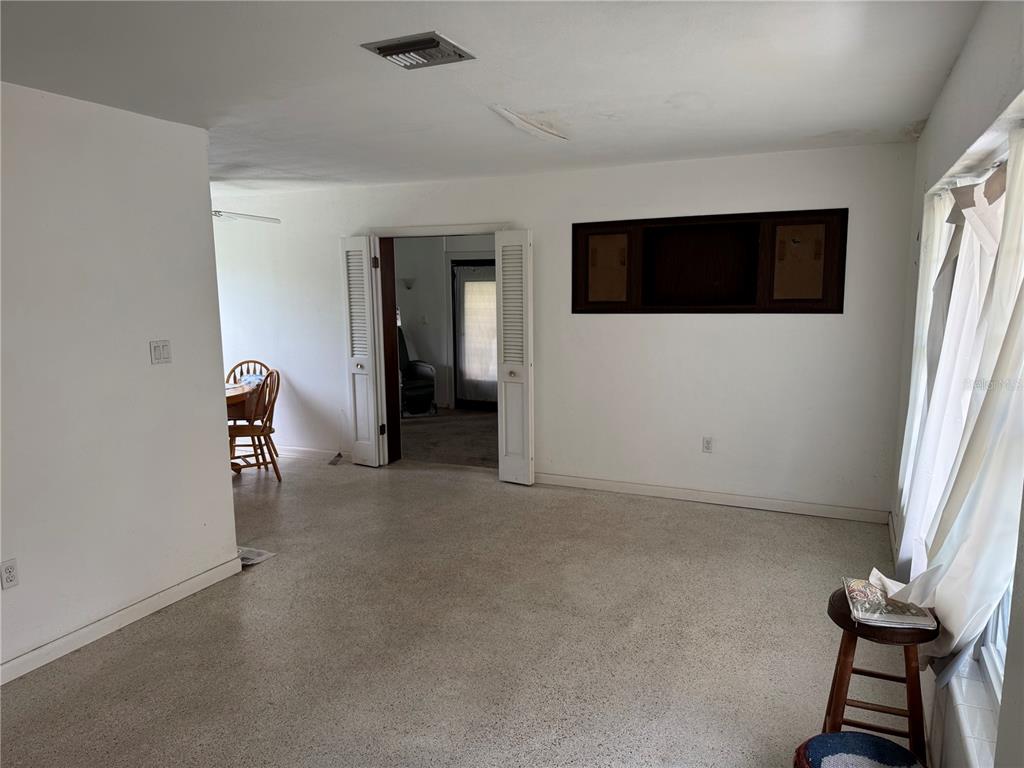 A living room with white walls, terrazzo flooring, and a doorway leading to another room — 27233 WHITMAN AVENUE, PUNTA GORDA, FL