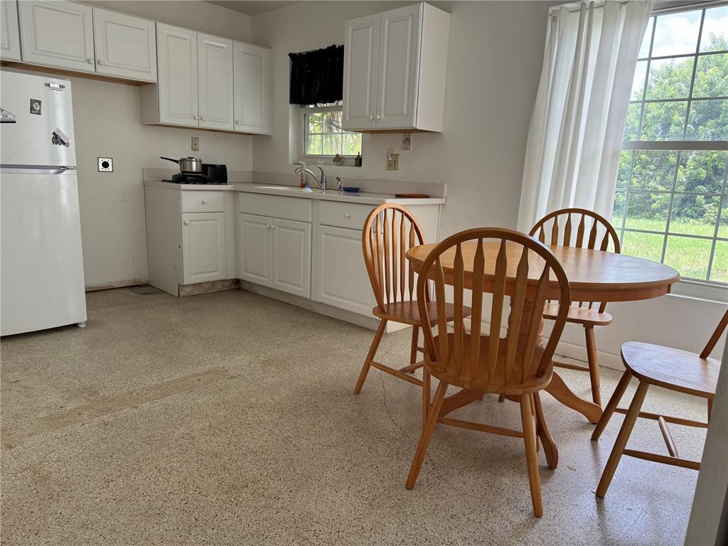 A kitchen features white cabinets, a refrigerator, a dining table with chairs, and speckled flooring — 27233 WHITMAN AVENUE, PUNTA GORDA, FL