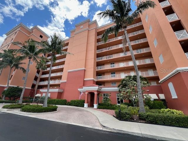 A low-angle view of a multi-story peach-colored apartment building with balconies and palm trees — 3191 MATECUMBE KEY ROAD UNIT 206, PUNTA GORDA, FL