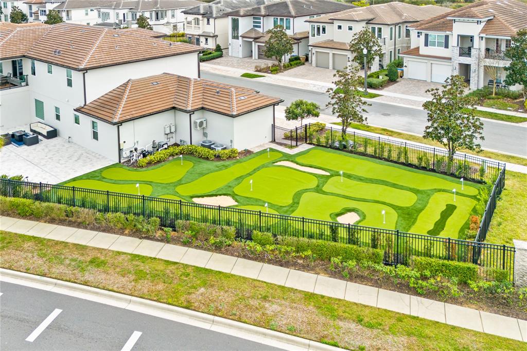An aerial view shows a residential backyard featuring a private putting green with sand traps — 7933 JACKS CLUB DRIVE, REUNION, FL