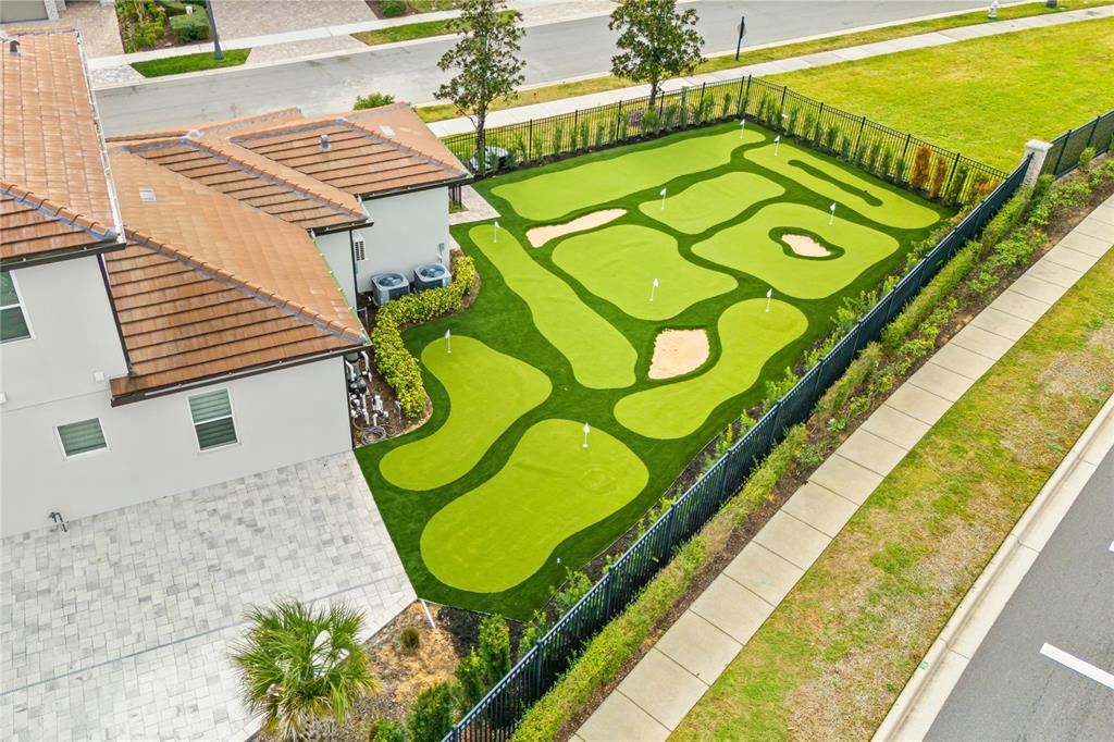 An aerial view of a residential backyard featuring a large, multi-hole artificial turf putting green — 7933 JACKS CLUB DRIVE, REUNION, FL