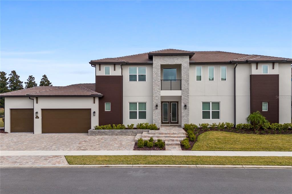 A two-story modern house with a stone facade, brown accents, and a three-car garage — 7933 JACKS CLUB DRIVE, REUNION, FL